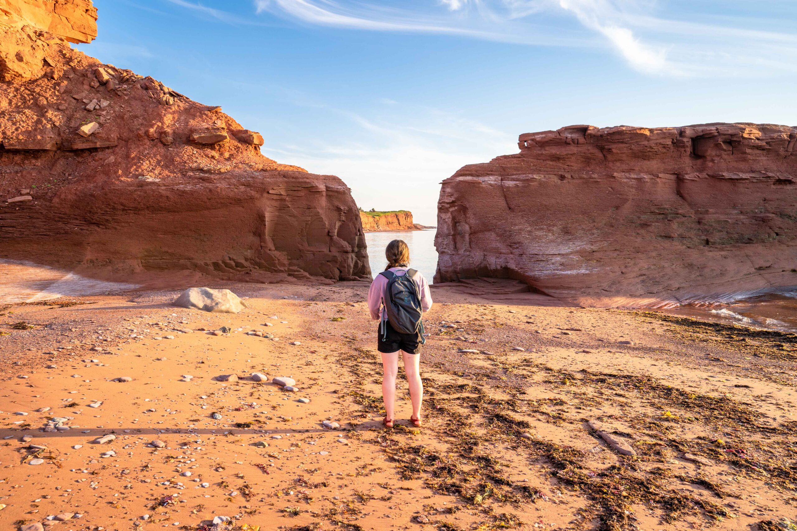 A traveller exploring the red sandstone coast of western Prince Edward Island