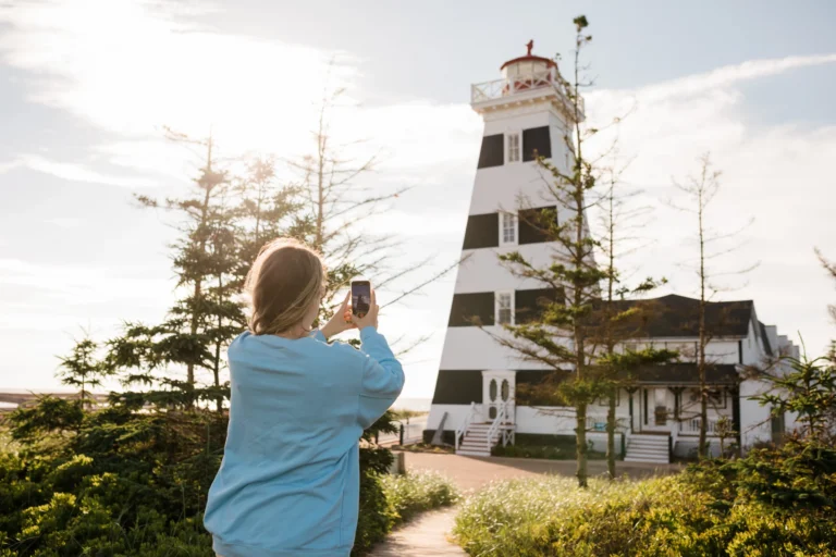 Visitor photographing the iconic West Point Lighthouse in Western Prince Edward Island.