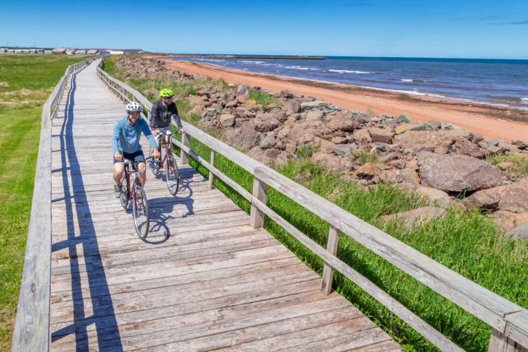 Cyclists riding along the boardwalk at Fisherman's Haven Park beside the beach in Western Prince Edward Island.